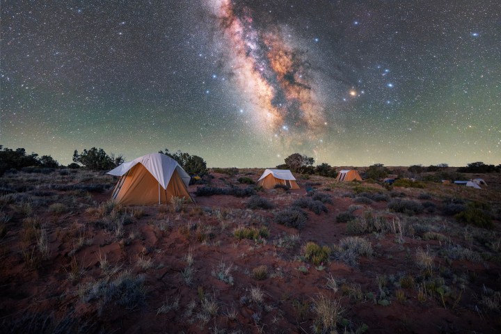 Tents under a vibrant, starry night sky with the Milky Way.