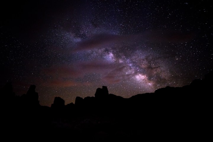 Starry night sky with Milky Way over silhouetted rocks.