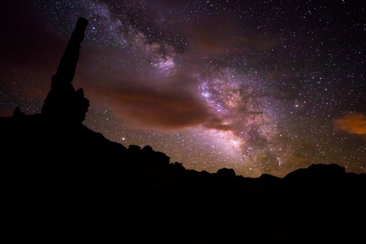 Starry night sky with Milky Way over dark rock formations.